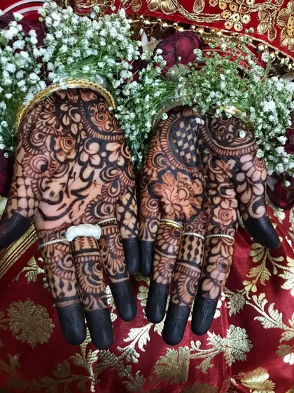 The deep, dark stain on the palms, adorned with rings and set against a vibrant background.