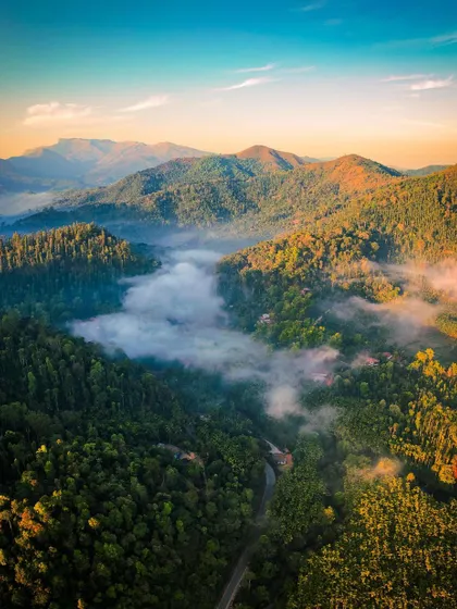 A stunning aerial view of the misty valleys around Kalasa in the Western Ghats. The vibrant colors of sunrise paint the sky and the landscape below.