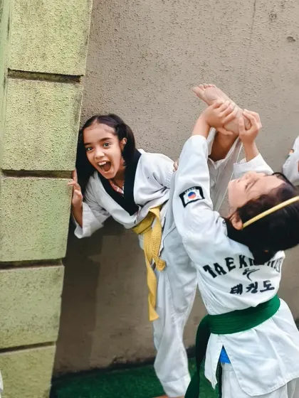 Two girls having fun while working on their high kicks. Training should be challenging, but it should also be enjoyable.