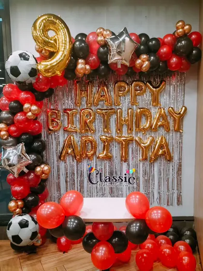 A 9th birthday party with a red, black, and gold football theme, featuring a balloon arch and personalized name balloons.