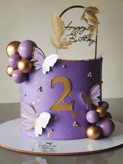 A lovely purple cake for a second birthday. The design features a cascade of purple and gold spheres and delicate white butterflies.
