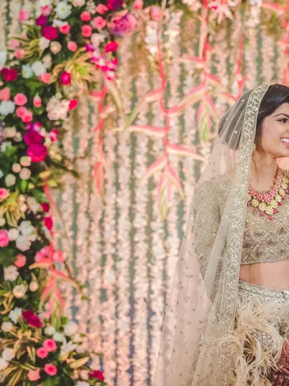 A beautiful candid of a bride, framed by a vibrant floral arch. Her joyful expression and the stunning decor come together to create a perfect wedding memory.