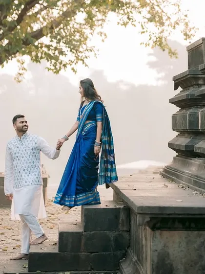 A gentle moment as he leads her down the ancient temple steps during their pre-wedding shoot.