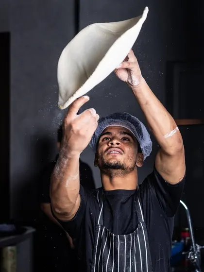 My pizza maestro at work. The dough for my pizzas undergoes a comprehensive process involving hot and cold proofing, which adds to the overall flavor and texture. Here, a chef shows off his dough-tossing skills.