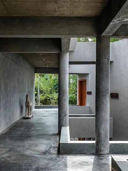 A wooden sculpture stands at the end of a corridor in Anahaspa, adding a touch of warmth and craft to the raw concrete structure.
