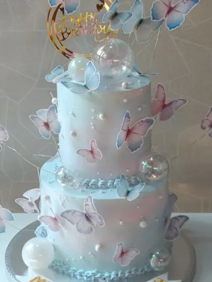 A dreamy two-tiered cake adorned with a flight of delicate wafer paper butterflies. The pearlescent finish gives it a magical shimmer.