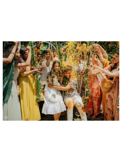 A wide shot of the couple's Haldi, showing all their friends and family participating in the flower shower.