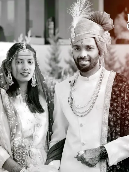 A classic black and white portrait of a couple in their traditional wedding attire.