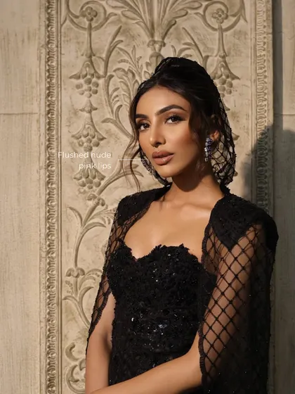 This shot highlights the flushed, nude-pink lips that perfectly balance the bold eyes, along with the elegant structure of the top knot hairstyle.