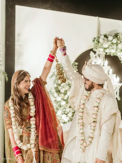 The couple celebrates their union, raising their hands in joy after the Varmala ceremony.