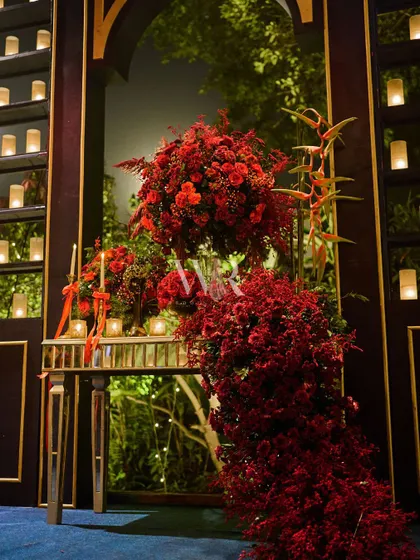 A detail of the cascading red floral arrangements at the entrance, showing the variety of textures and shades of red used to create a lush, organic feel.