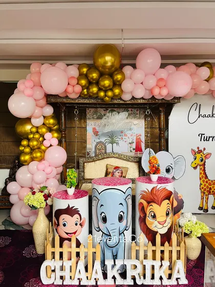 Another angle of the pink and gold jungle theme, showing the full balloon arch and character stands.