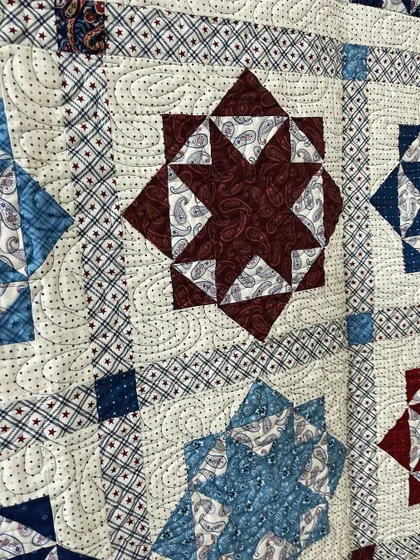 A detailed view of a Lone Star quilt, where the spaces between the stars are filled with a classic paisley-style quilting design.