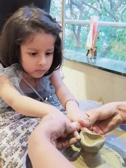 A focused moment as a young girl learns to make a diya. This traditional craft connects children to Indian culture in a tangible way.