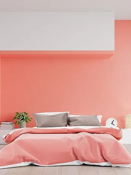 This bedroom uses architectural colour blocking, with coral pink on the main walls and a crisp white block to frame the bed area. This creates a built-in headboard effect and adds modern dimension to the room.