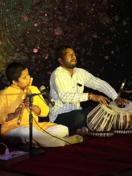 The dramatic stage lighting highlights the focus and dedication of our student and teacher during a classical music performance. Every detail of the Dhwani Kala Mahotsav is curated for a magical experience.