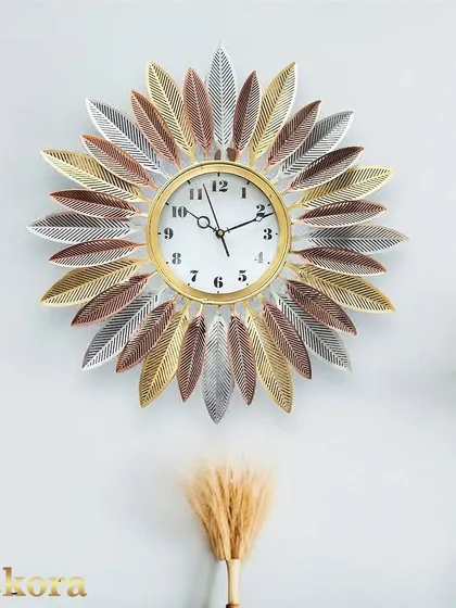 This sunburst clock is crafted with multi-toned metal leaves in shades of gold, silver, and bronze, giving it a warm, rustic feel.