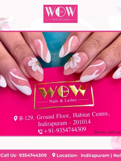 A modern French manicure on almond-shaped extensions. This design features a clean white tip with abstract swirls and 3D floral accents for a unique and artistic touch.