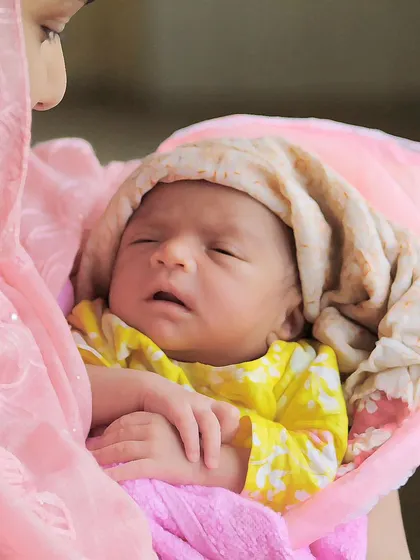 A tender lifestyle moment of a mother holding her sleeping newborn. These at-home sessions are perfect for capturing the real, loving environment of a new family.