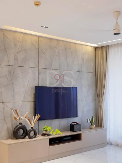 The TV unit is styled with minimal decor to maintain a clean and uncluttered look, complemented by soft, full-length curtains.