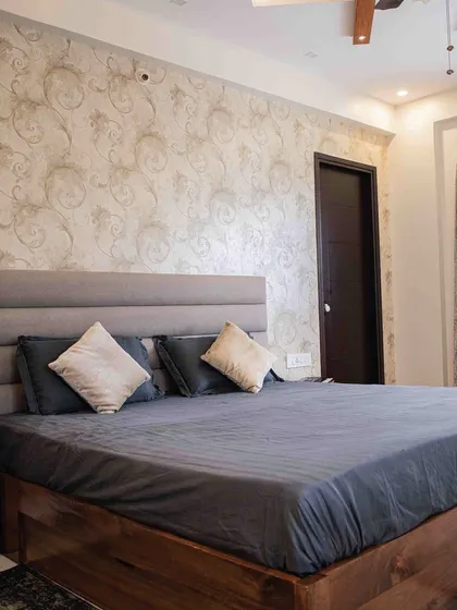 This bedroom is a serene haven of calm and functionality. The feature wall with patterned wallpaper, combined with a simple upholstered headboard, creates a soothing backdrop for rest.