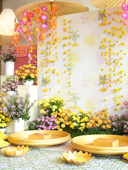 The 'phoolon ki holi' setup for the Haldi, with a wall of falling flowers and large platters ready for the ceremony.