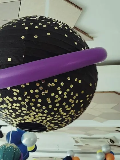 To create a truly immersive space theme, we even decorated the ceiling. This hanging planet lantern, made with a paper lantern and a balloon ring, added another layer of cosmic fun to the party atmosphere.