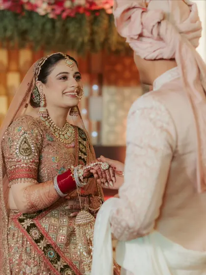 A beautiful, candid moment during the wedding ceremony. The bride, Raghavi, looks at her groom, Shivam, with a smile full of love and happiness.