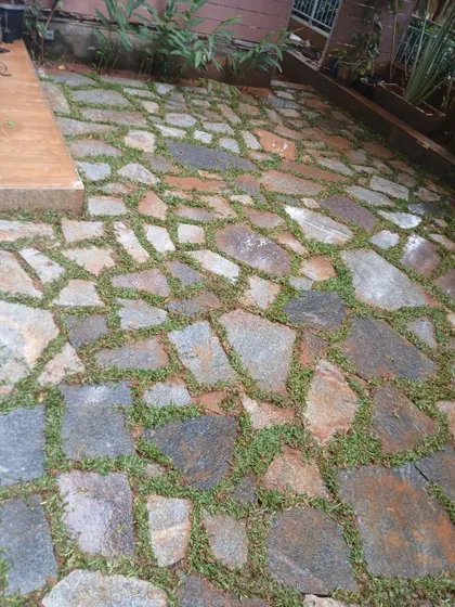 A rustic garden path made from irregularly shaped flagstones with grass growing in between. This style of hardscaping provides a natural, organic feel to the garden.