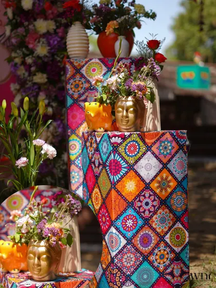 A cluster of decorative pedestals in varying heights, all wrapped in a colorful mosaic-patterned fabric. Topped with unique golden and orange vases, this corner was a visual delight.