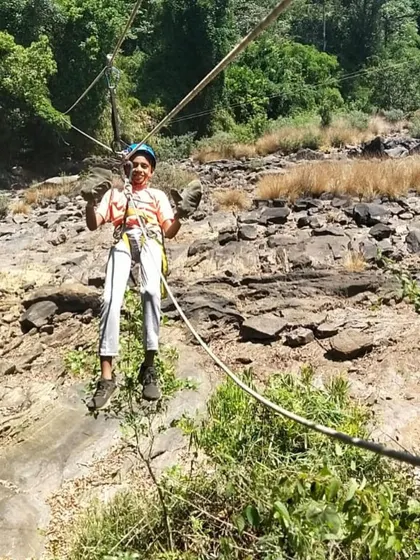 A young camper flashes a peace sign while enjoying a safe and exciting rope activity.