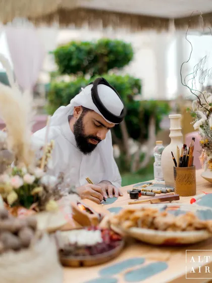 We love incorporating local culture into our destination weddings. Here, a calligrapher creates personalized art for guests at our 'Markets of the Middle East' event in Doha.