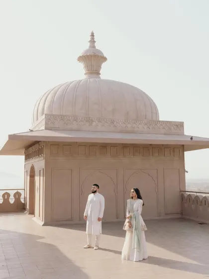 A wide, minimalist portrait of Amani and Tj against the rooftop architecture of the Fairmont Jaipur, emphasizing space and grandeur.