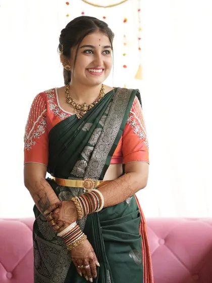 A smiling bride, her custom-designed blouse adding a touch of modern elegance to her traditional saree.