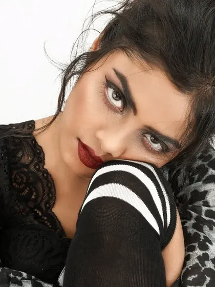 An intense, up-close portrait with a focus on the eyes. This look uses a dramatic winged eyeliner and a deep red lip to create a bold, gothic-inspired aesthetic for a themed photoshoot.