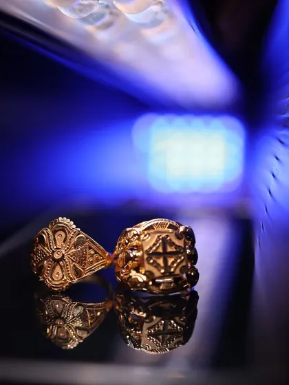 A creative and artistic shot of the engagement rings, reflecting on a surface with a dramatic blue light background.