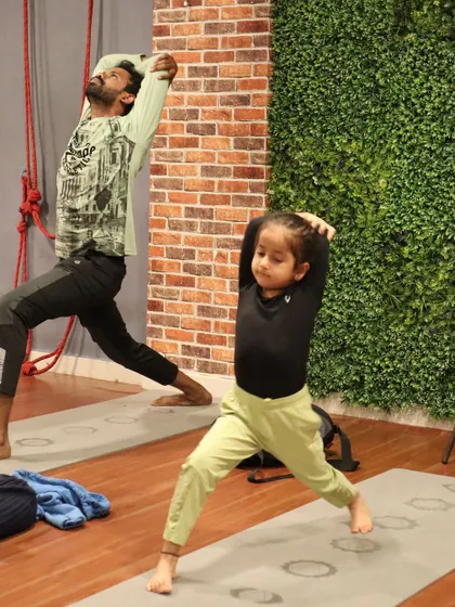 A father and daughter practice Virabhadrasana I (Warrior I) side-by-side. Yoga can be a beautiful activity for the whole family.