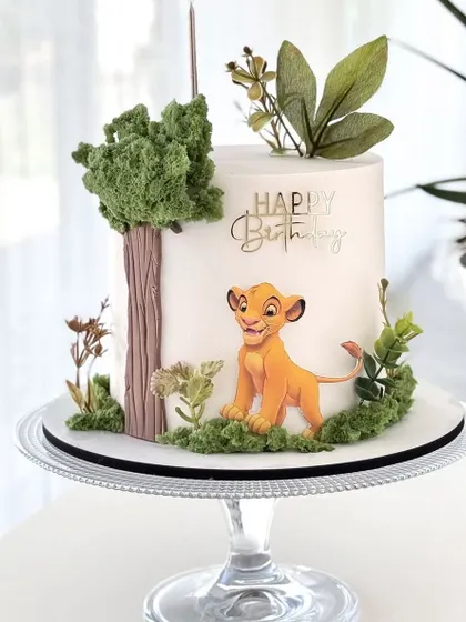 A beautiful and artistic take on a Lion King theme. This cake features a hand painted Simba against a clean white backdrop, surrounded by delicate, realistic sugar foliage. A modern and elegant design for a fan of the classic movie.