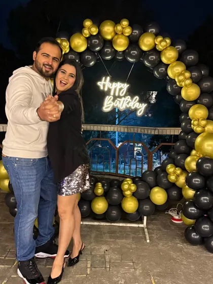 A couple dancing in front of the balloon arch, showing how the decorations create a perfect party atmosphere.