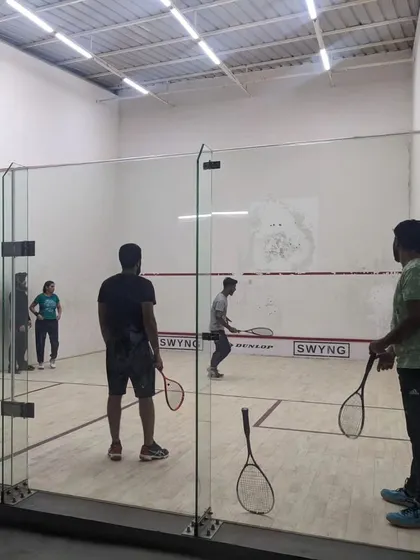 Players practicing drills inside the squash court during a group session. We structure our coaching to accommodate multiple players while focusing on individual skill development.