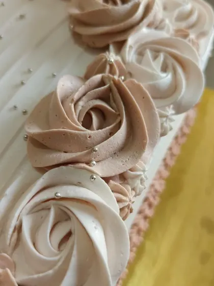 A close-up of the beautiful two-tone piped rosettes on a large corporate order cake.