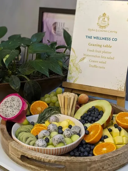 A vibrant and healthy fruit platter designed for The Wellness Co. This board is overflowing with exotic fruits like dragon fruit, kiwi, and melon, alongside oranges and blueberries, promoting a message of fresh, clean eating.