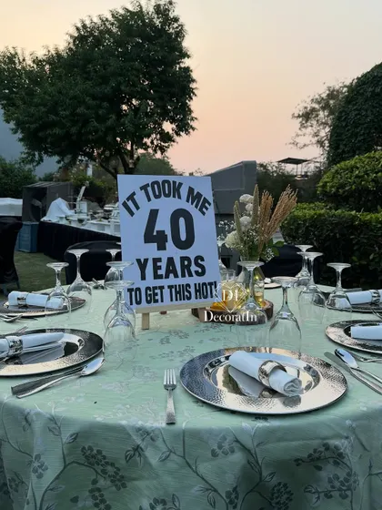 A full view of a guest table, showing the witty sign as a centerpiece, complemented by elegant silverware and a simple floral arrangement.