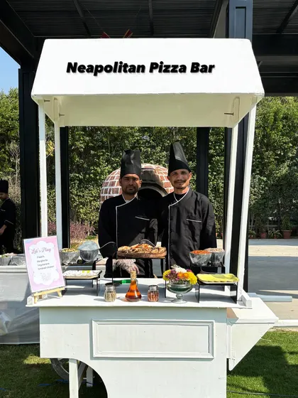 My Neapolitan Pizza Bar on wheels. This setup features my two chefs proudly presenting a freshly baked pizza, ready to bring the full pizzeria experience to your event.