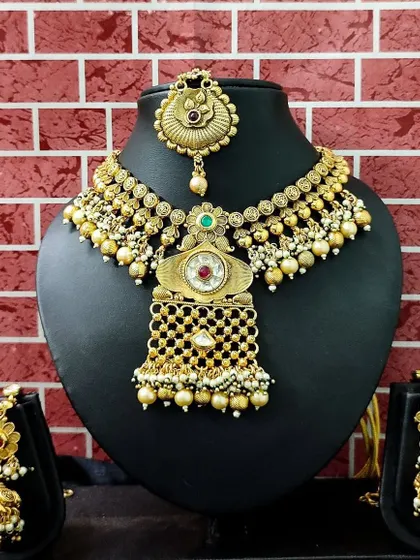 This antique-finish temple jewellery set is available for rent. It includes a unique choker, matching earrings, and a maang tikka, perfect for a traditional ceremony.