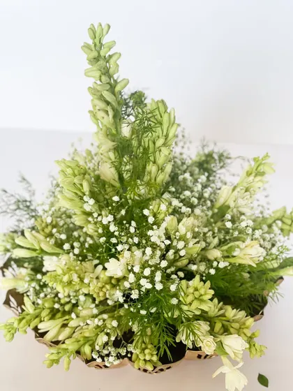 This image highlights the beauty of simplicity. A basket filled with fresh, fragrant tuberose (rajnigandha) and baby's breath. This kind of floral gift is a sustainable and elegant choice that brings natural beauty indoors.