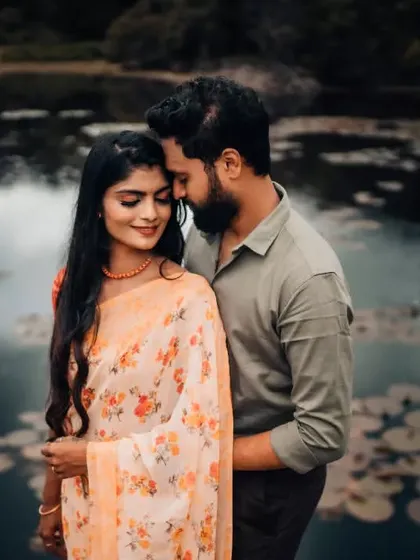 An intimate pre-wedding portrait by a lake filled with water lilies, creating a soft and romantic atmosphere.