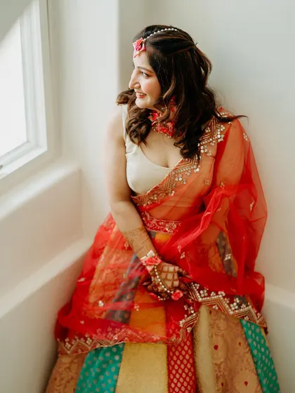 A quiet moment of anticipation for the bride, dressed in a colorful lehenga for her Haldi ceremony.