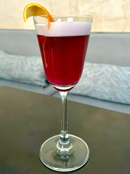 A vibrant, deep red cocktail in a wine glass. The colour is intense, promising a bold and flavourful experience.