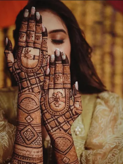 A creative pose showing off a full bridal mehndi design. The pattern is geometric and traditional, with check patterns and arches, perfect for a bride who loves classic art.